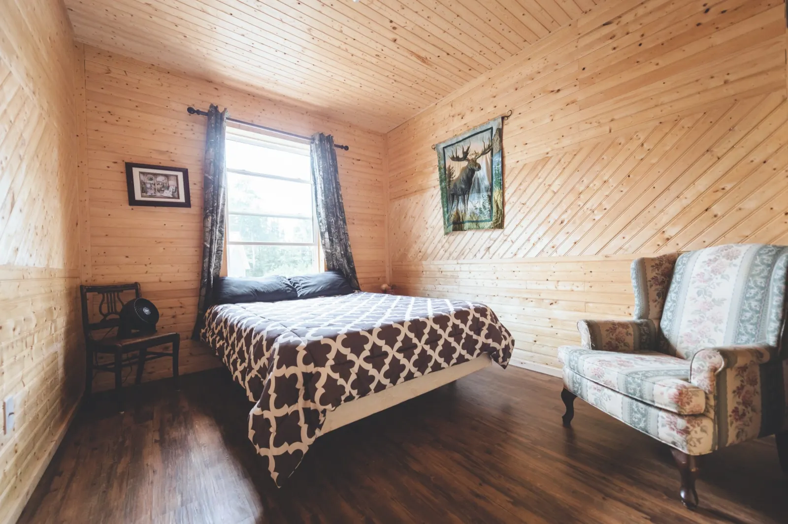 A bedroom with a queen bed and an armchair
